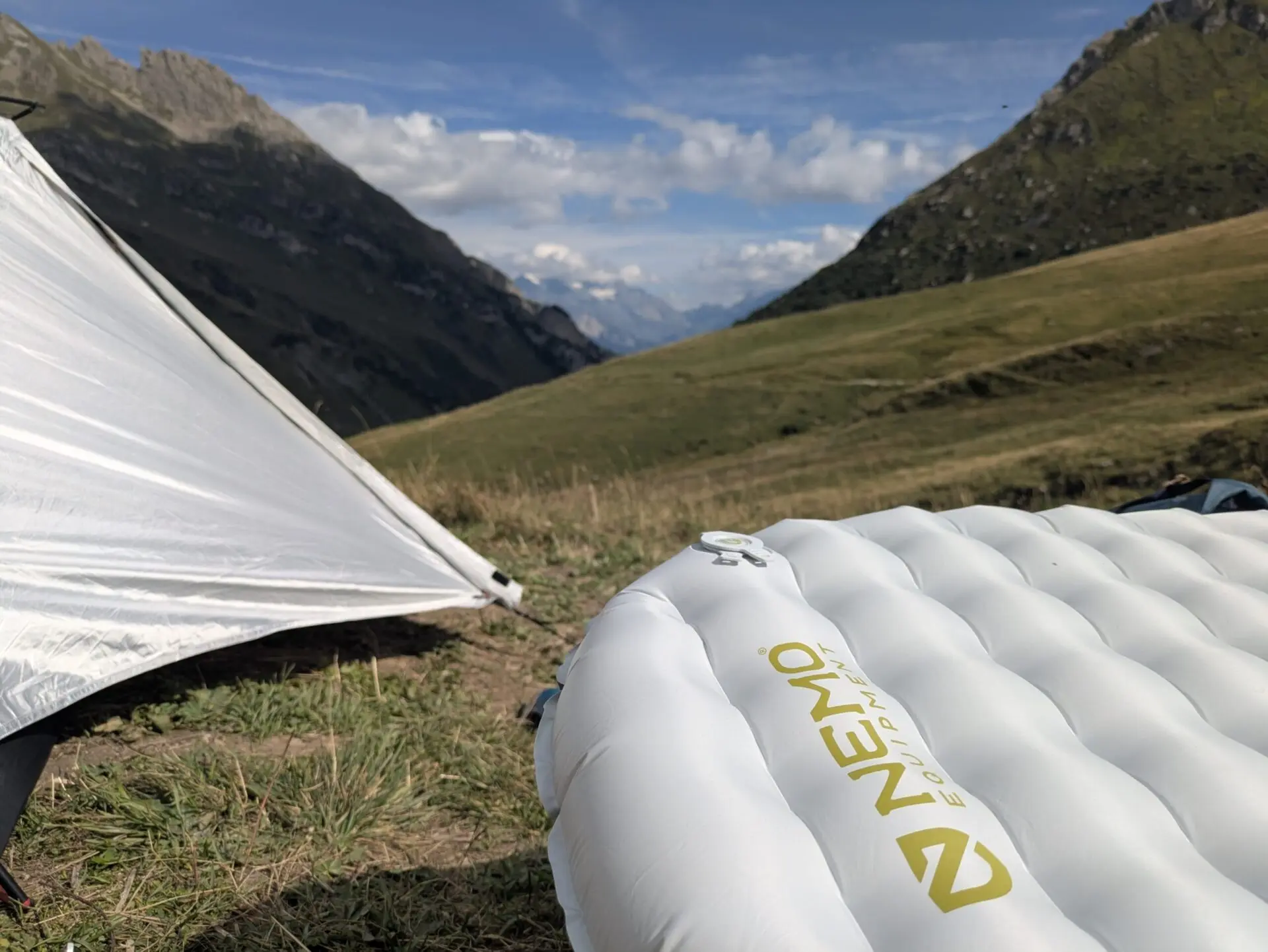 Matelas gonflable posé devant une tente au bivouac en montagne