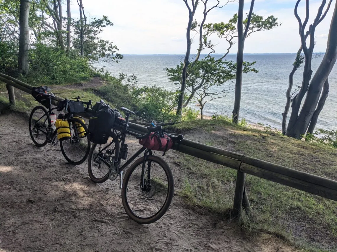 Deux gravels chargés de sacoches bikepacking appuyés sur une barrière au bord de la mer Baltique