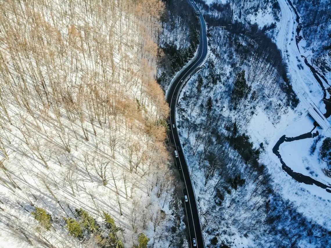 Route sinueuse enfouie sous la neige au milieu d une forêt en hiver