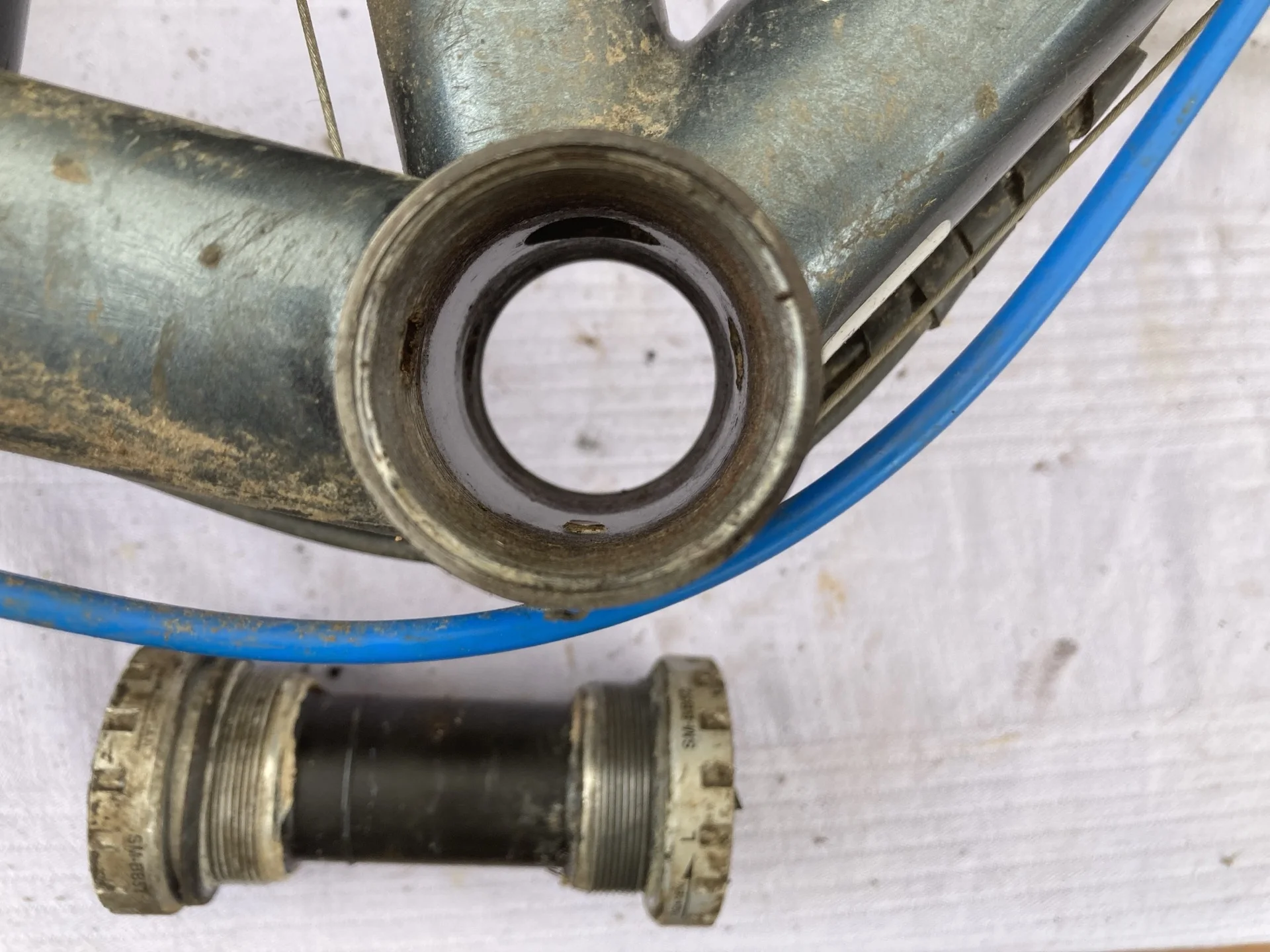 Logement de boîtier de pédalier ouvert sur un cadre vélo, avec la cartouche démontée posée à côté