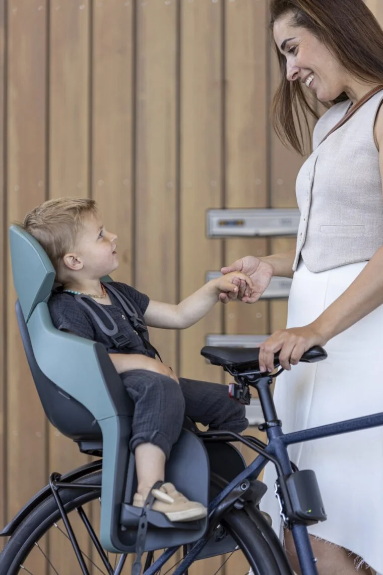 Parent qui règle le harnais d'un enfant assis dans un siège vélo arrière