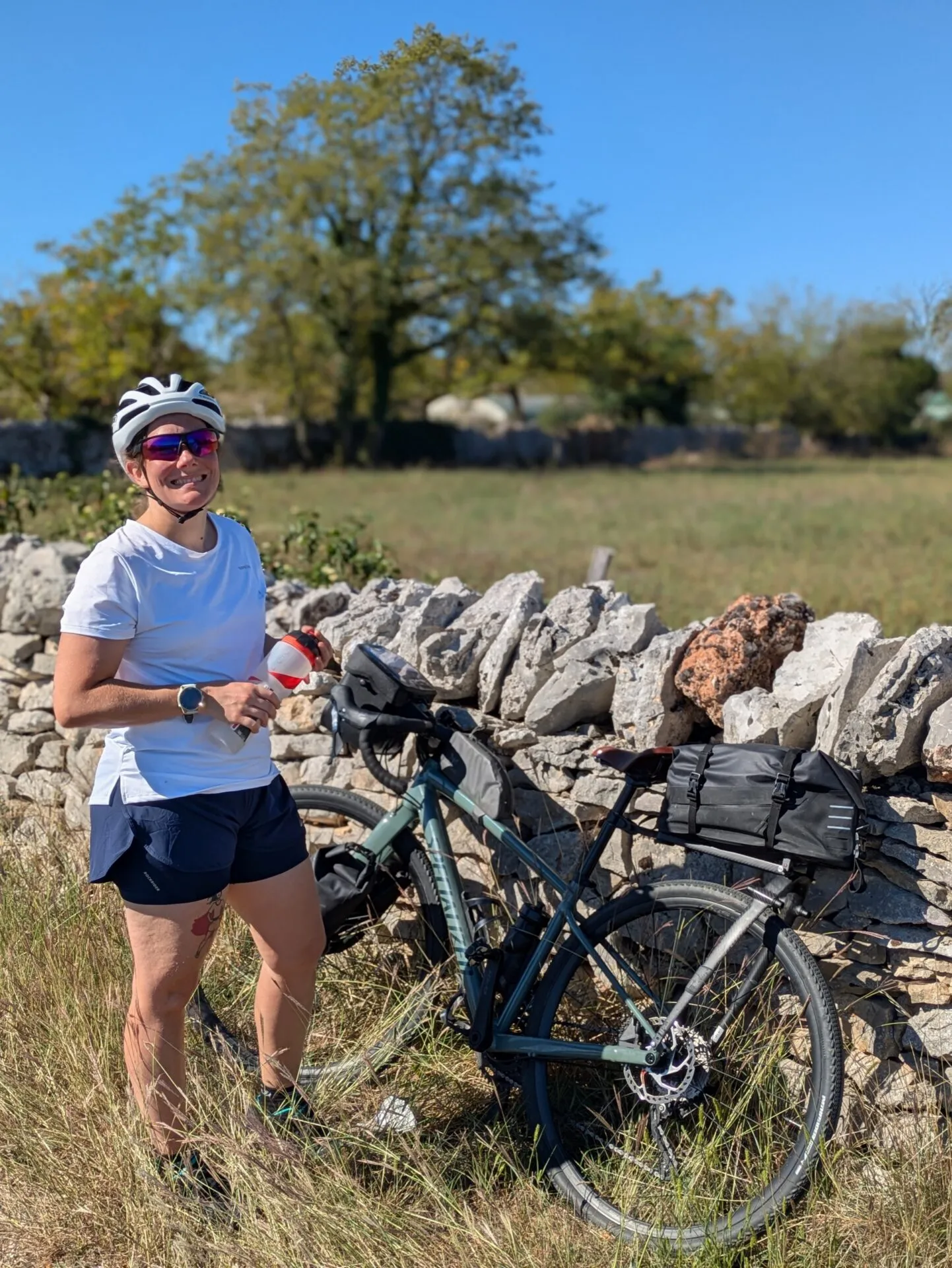 Morgane et son vélo de voyage devant un muret du causse du Quercy