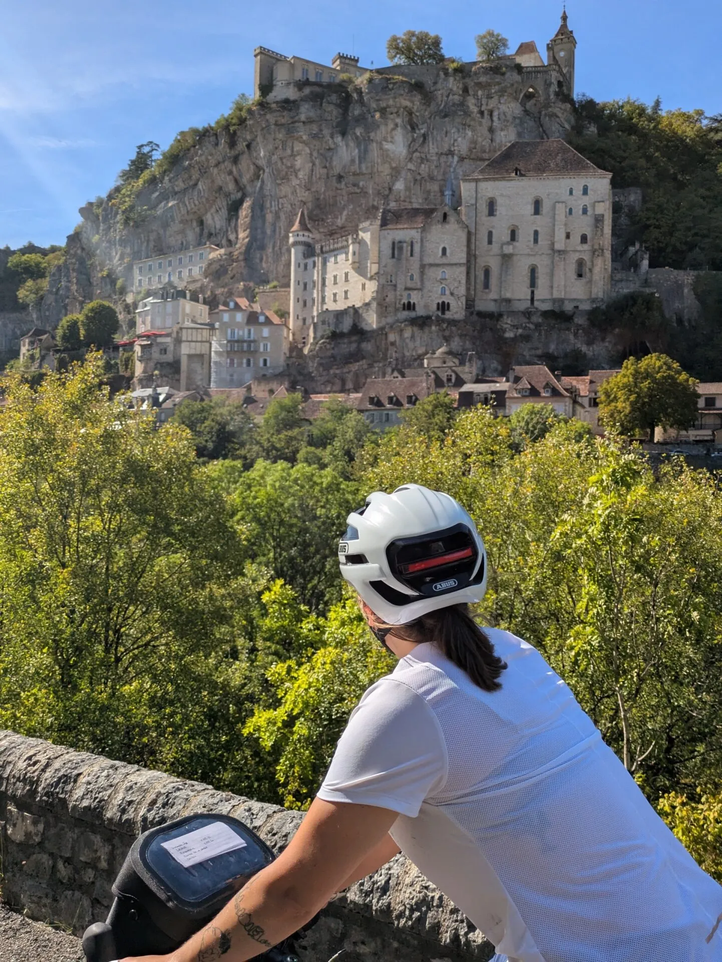 Morgane à vélo face à Rocamadour accroché à sa falaise
